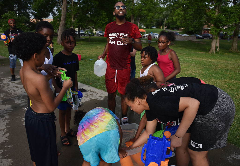Water gun fight participants step away from the fight to refill their guns from a water tub